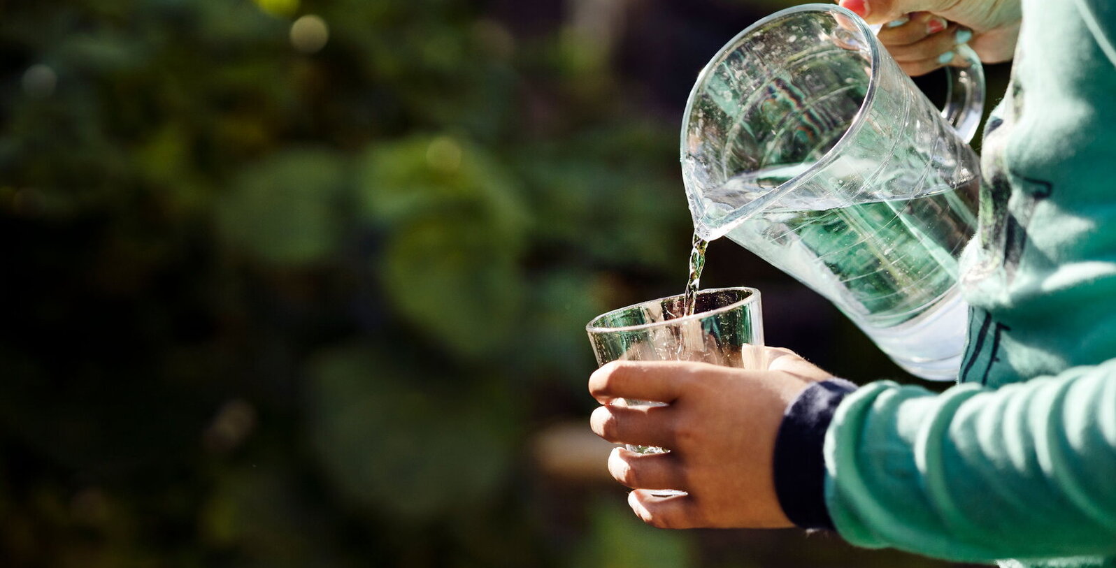 Bild på en person som häller upp ett glas vatten.